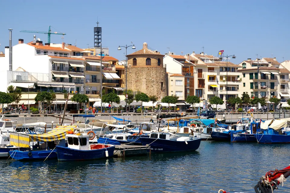 Barques de pesca al port de Cambrils amb la Torre del Port i el passeig marítim de fons
