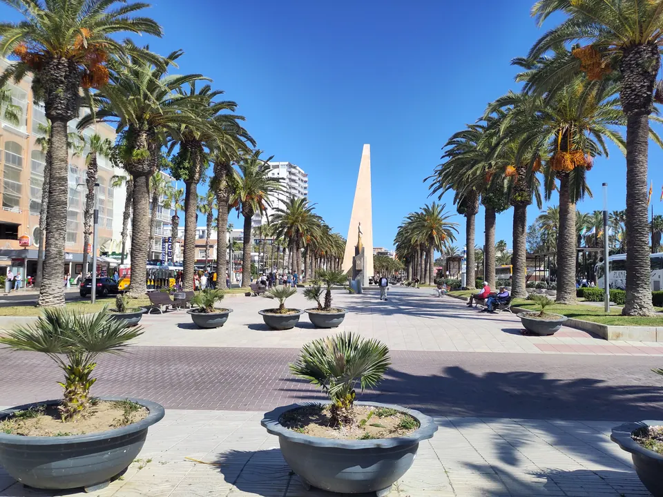 Passeig Jaume I de Salou amb palmeres, jardineres i un obelisc al fons sota un cel blau