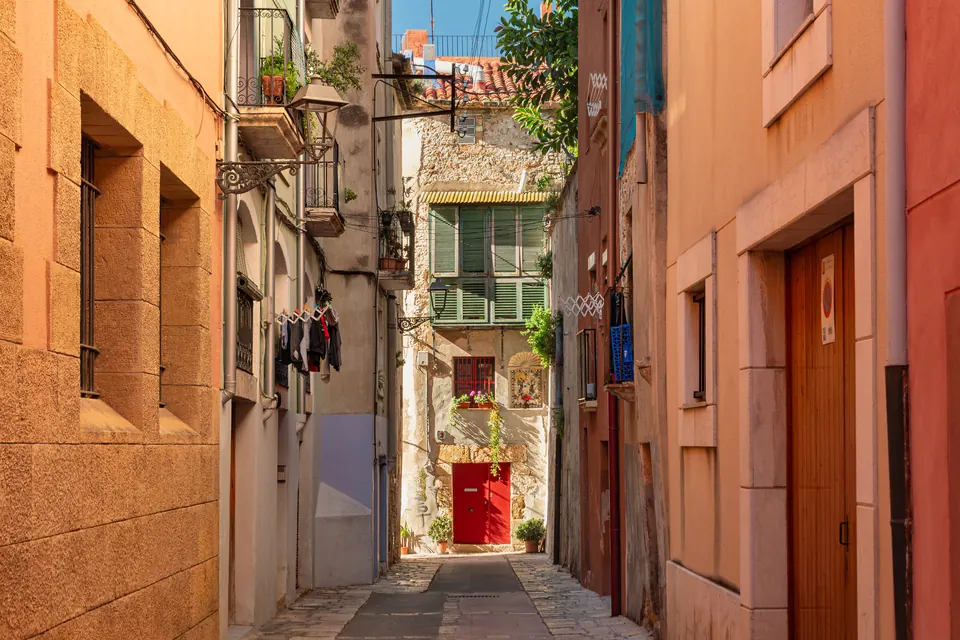 Carreró estret de la Part Alta de Tarragona amb façanes de colors càlids i una porta vermella al fons